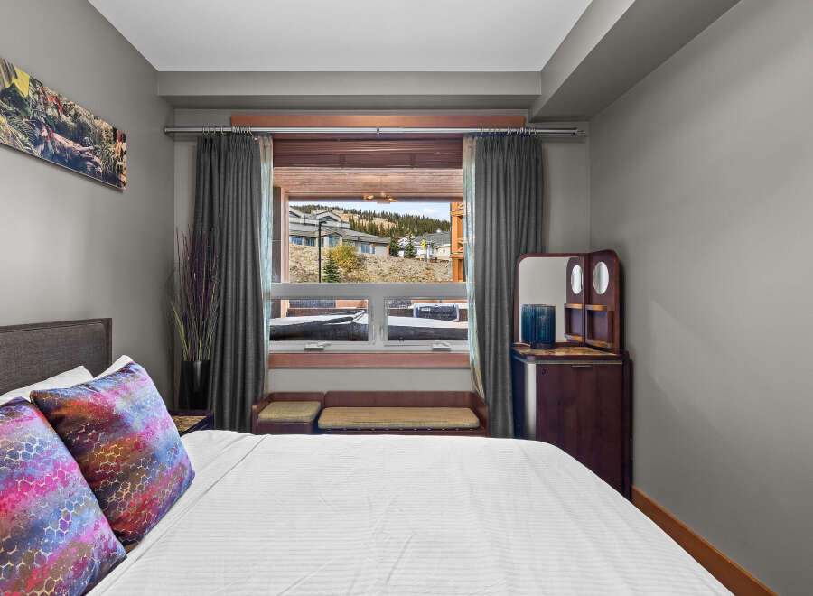 Experience comfort and style in this beautifully appointed bedroom, featuring a plush king-sized bed adorned with vibrant, decorative pillows.