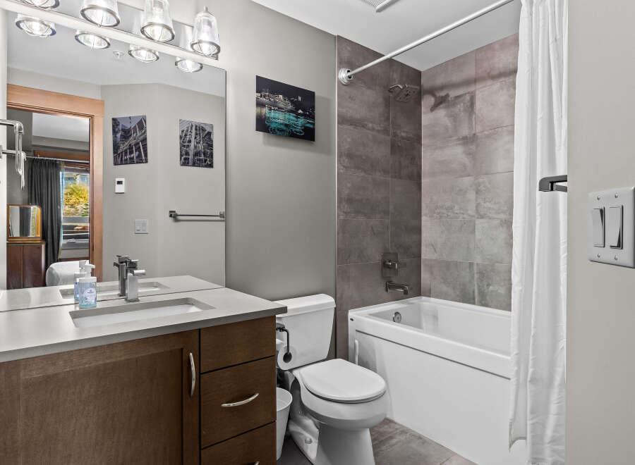 This modern bathroom features a sleek vanity with a stone countertop and a vessel sink, complemented by a large mirror with overhead lighting.