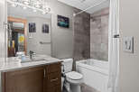 This modern bathroom features a sleek vanity with a stone countertop and a vessel sink, complemented by a large mirror with overhead lighting.