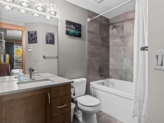 This modern bathroom features a sleek vanity with a stone countertop and a vessel sink, complemented by a large mirror with overhead lighting.