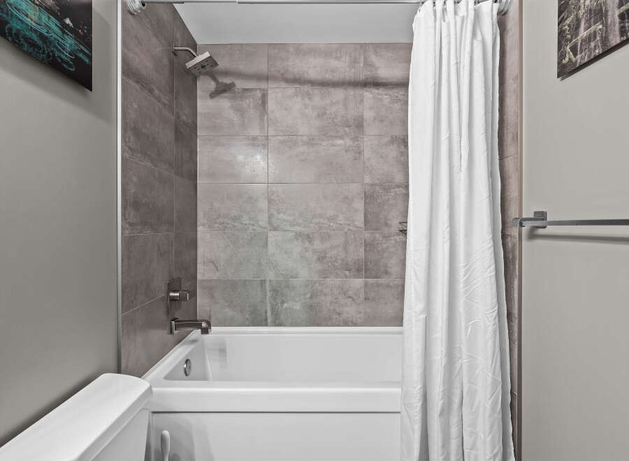 Experience modern comfort in this bathroom featuring a sleek bathtub and shower combination.