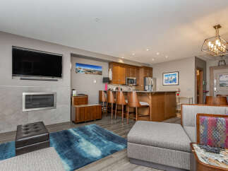 Experience modern living in this open-concept condo, featuring a sleek fireplace and a mounted flat-screen TV.