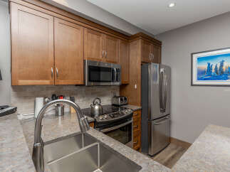 This modern kitchen boasts sleek stainless steel appliances, including a refrigerator, microwave, and oven with a stovetop.
