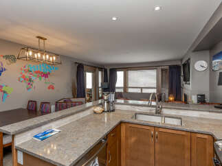 This modern kitchen boasts a spacious island with a granite countertop, perfect for meal preparation and casual dining.
