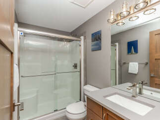 This modern bathroom features a spacious glass-enclosed shower with a sleek chrome handle and a built-in bench.