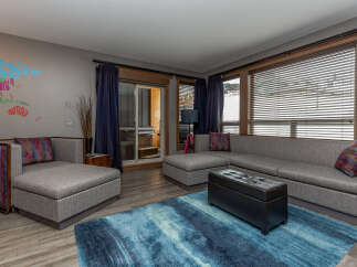 Experience ultimate comfort and style in this modern living room, featuring a spacious sectional sofa perfect for gatherings and a plush blue abstract rug that adds a vibrant touch.