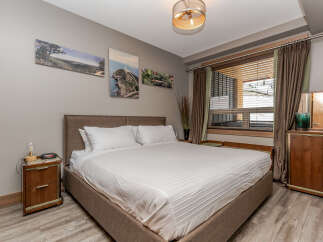 Experience comfort and style in this beautifully appointed bedroom, featuring a plush king-size bed with crisp white linens and a sophisticated upholstered headboard.