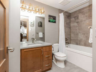 This modern bathroom features a sleek vanity with a quartz countertop and ample storage.