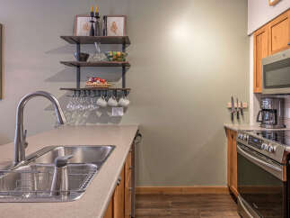 This modern kitchen features a sleek stainless steel sink and faucet, complemented by warm wooden cabinetry.