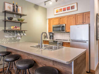 This modern kitchen features a spacious island with a double sink and ample counter space, perfect for meal preparation and casual dining.