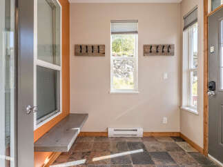 Welcome to this charming entryway, featuring a rustic wooden bench perfect for removing shoes after a long day.