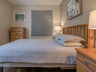 This inviting bedroom features a comfortable queen-size bed with crisp, striped linens and plush pillows, perfect for a restful night's sleep.
