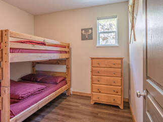 This charming bedroom features a sturdy wooden bunk bed with deep burgundy bedding, perfect for accommodating guests or children.