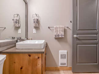 This modern bathroom features a stylish vessel sink atop a warm wooden vanity, complemented by a sleek chrome faucet.