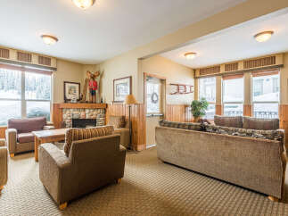 Cozy living room with a stone fireplace and large windows offering scenic winter views.