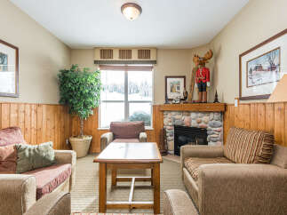 Cozy living room featuring a stone fireplace and a large window with a snowy landscape view.