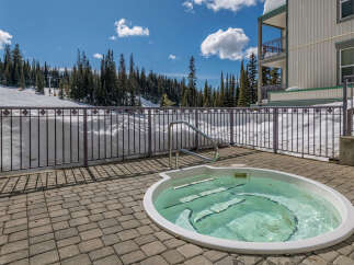Enjoy a relaxing soak in the private hot tub on your patio, offering stunning views of the snow-covered ski slopes and surrounding evergreen forest.