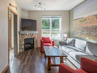 Cozy living room featuring a stone fireplace and a large flat-screen TV.