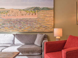 Experience the charm of this inviting living space, featuring a large, textured tapestry depicting a desert village scene that adds a unique artistic flair.