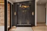 Step into a modern entryway featuring a striking dark wood waterfall feature, complemented by elegant wall sconces and a unique pendant light.