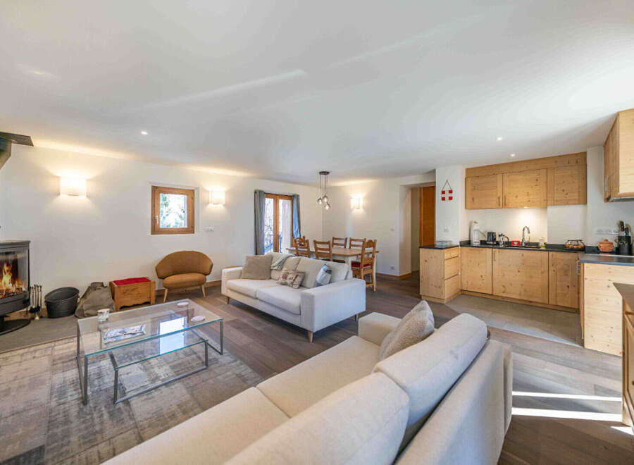 Experience cozy living in this charming open-plan space, featuring a modern wood-burning stove and a fully equipped kitchen with ample wooden cabinetry.