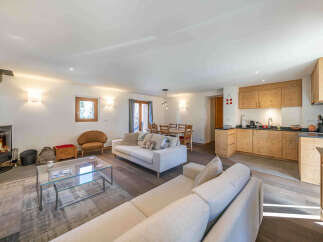 Experience cozy living in this charming open-plan space, featuring a modern wood-burning stove and a fully equipped kitchen with ample wooden cabinetry.