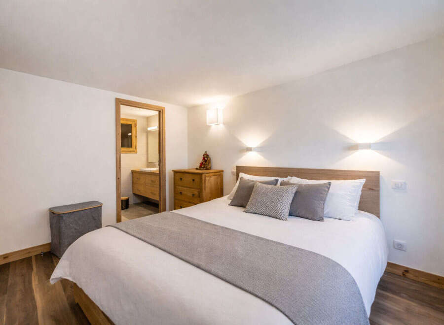 This cozy bedroom features a comfortable queen-size bed with crisp white linens and plush grey pillows, perfect for a restful night's sleep.