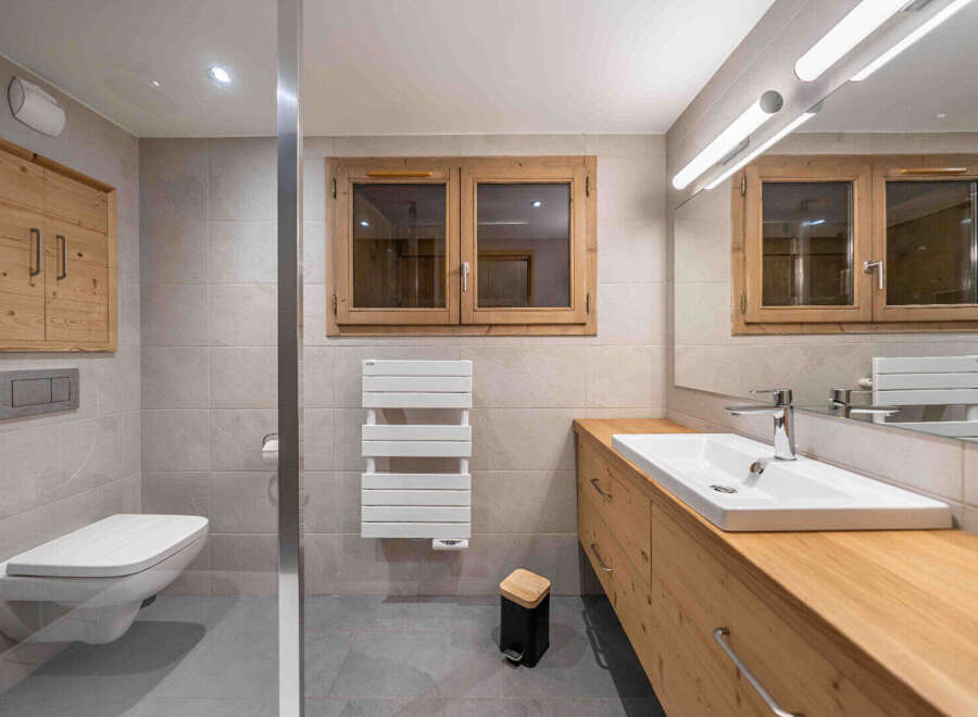Experience luxury and comfort in this modern bathroom, featuring a sleek wall-mounted toilet and a spacious vanity with ample storage.