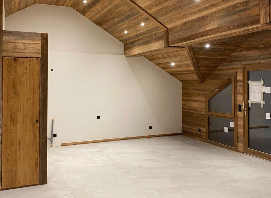 Experience the rustic charm of this unfinished attic space, featuring a stunning wooden beamed ceiling and walls that evoke a cozy mountain lodge feel.