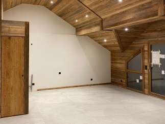 Experience the rustic charm of this unfinished attic space, featuring a stunning wooden beamed ceiling and walls that evoke a cozy mountain lodge feel.