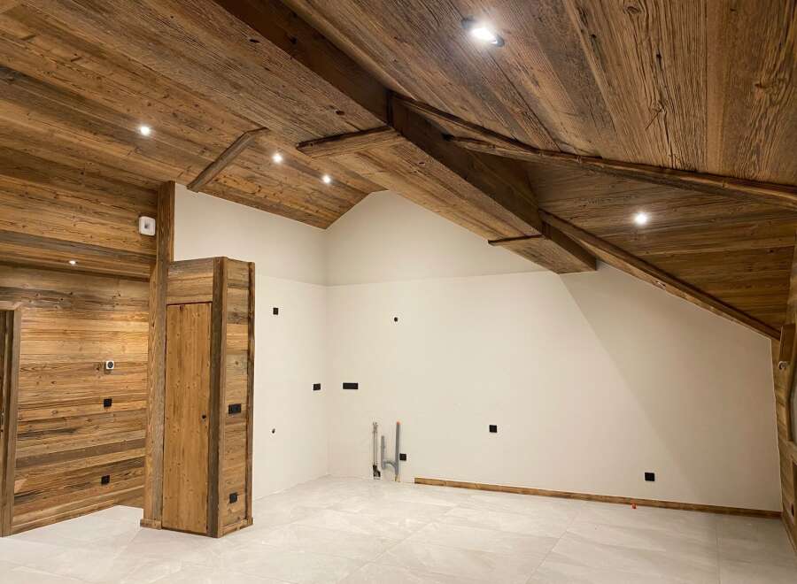 Experience rustic charm and modern comfort in this beautifully appointed room, featuring a stunning wooden-paneled ceiling with exposed beams and recessed lighting.
