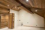 Experience rustic charm and modern comfort in this beautifully appointed room, featuring a stunning wooden-paneled ceiling with exposed beams and recessed lighting.
