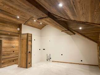 Experience rustic charm and modern comfort in this beautifully appointed room, featuring a stunning wooden-paneled ceiling with exposed beams and recessed lighting.