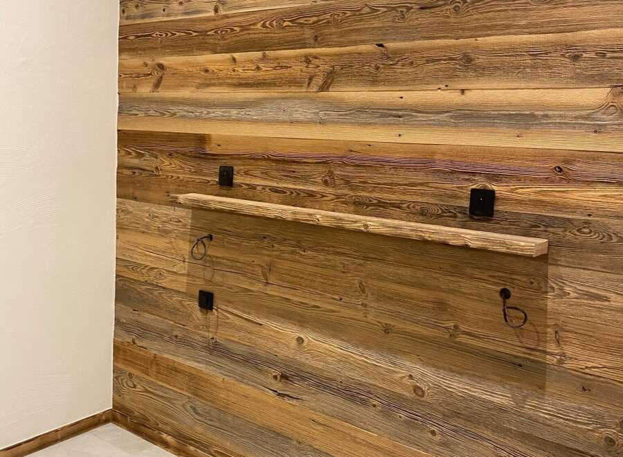 Experience rustic charm with this beautifully paneled wooden wall, featuring a unique floating shelf perfect for displaying decor.