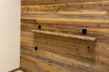 Experience rustic charm with this beautifully paneled wooden wall, featuring a unique floating shelf perfect for displaying decor.
