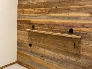 Experience rustic charm with this beautifully paneled wooden wall, featuring a unique floating shelf perfect for displaying decor.
