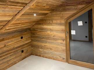 Experience rustic charm and modern comfort in this beautifully appointed room featuring warm, natural wood paneling on the walls and ceiling.