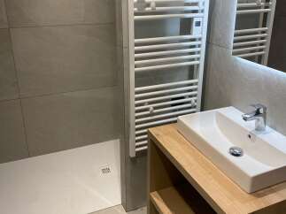 This modern bathroom features a sleek white sink atop a warm wooden vanity, complemented by a chrome faucet.