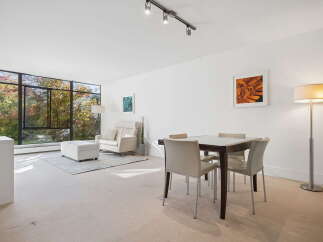 Experience breathtaking natural views from this spacious living and dining area, featuring a wall of windows that flood the space with natural light.