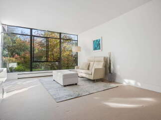 Experience breathtaking natural views from this living room, featuring expansive floor-to-ceiling windows that showcase a vibrant autumn landscape.