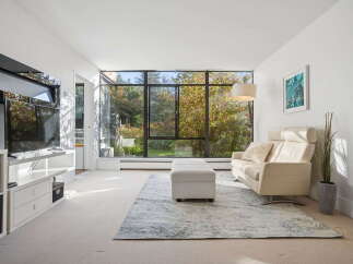Experience modern living in this bright and airy living room, featuring a large wall-mounted TV and a sleek entertainment center.