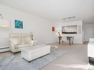 This bright and airy living space features a comfortable white leather sofa paired with a matching ottoman, perfect for relaxation.