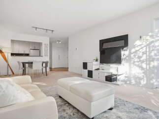 This bright and airy living space features a modern entertainment center with a sleek fireplace and a large flat-screen TV.