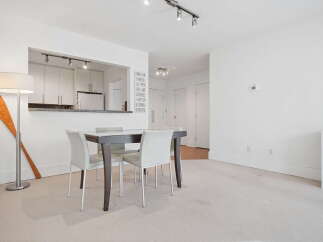 This bright and airy dining area features a sleek dark wood dining table with four white upholstered chairs, perfect for intimate gatherings.