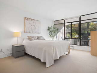 Experience comfort and style in this inviting bedroom, featuring a plush bed adorned with a textured white blanket and decorative pillows.