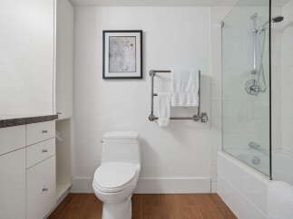 This modern bathroom features a sleek white vanity with ample storage, complemented by a granite countertop.