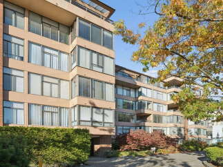 Discover modern living in this stunning apartment building, featuring a striking beige facade and abundant natural light pouring through large windows.