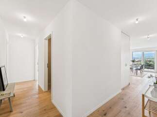 Step into this bright and airy hallway featuring elegant hardwood floors that lead to a spacious living area.