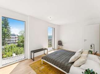 Experience modern living in this bright bedroom featuring a comfortable bed with plush pillows and a stylish grey quilt.