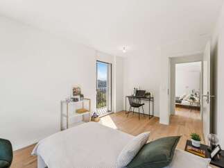 Experience modern living in this bright bedroom featuring a comfortable bed, a dedicated workspace with a desk and chair, and a balcony with stunning views.
